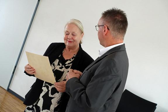 Der Bürgermeister übergibt eine Urkunde an Frau Conrad